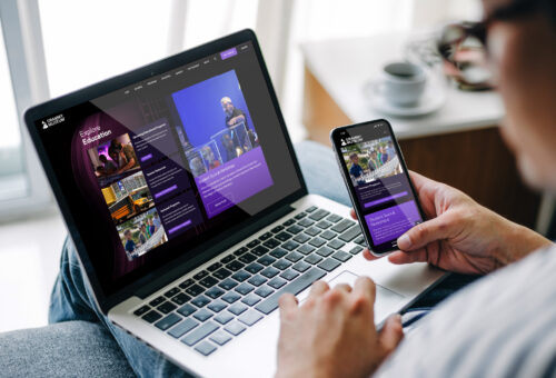 A woman interacts with the GRAMMY Museum Mississippi website on a laptop and smartphone, illustrating a seamless and user-friendly digital experience across devices.